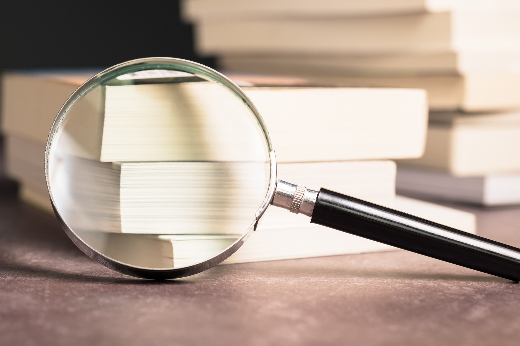 Closeup Mafnifying Glass Rest on the Pocket Books on Pile.